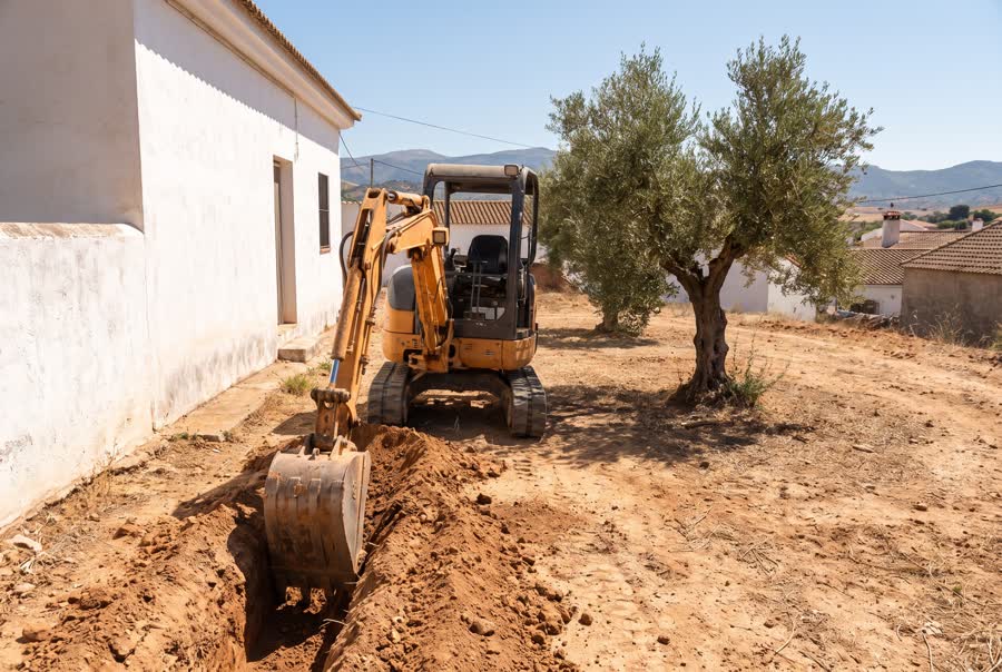 Miniexcavadora de 1,8 toneladas abriendo una zanja en una obra residencial